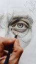 Vertical closeup of artist hand drawing human portrait woth pencil on white sheet of paper Royalty Free Stock Photo