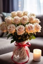 vertical closeup of a beautiful bouquet of white roses flowers in a glass vase in cozy modern living room