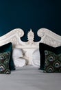 Vertical closeup of a bed with a white headboard, adorned with a peacock pillow Royalty Free Stock Photo