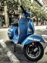 Vertical closeup of a blue classic Piaggio Vespa scooter on the street