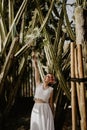 Vertical closeup of a bride holding bouquet with a hand up and smiling sunlit straws background