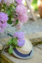 Vertical closeup of a bunch of colorful hydrangeas outdoors with a straw hat on the wooden desk
