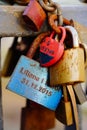 Vertical closeup of bunch of rusty love locks with names in on metal railing