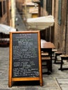 Vertical closeup of a cafe menu presented on a black board in a narrow Italian street