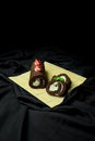 Vertical closeup of chocolate swiss rolls with berries in a straw plate, dark background