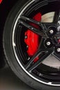 Vertical closeup Corvette C8 Stingray wheel and brake caliper, red brake, and piano wheel