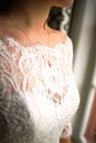 Vertical closeup of a detail of a bride& x27;s white wedding dress and a beautiful necklace