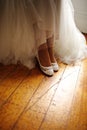 Vertical closeup of a detail of a bride's white wedding dress and shoes