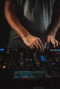 Vertical closeup of a DJ working under the lights against a dark background in a studio