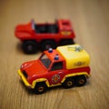 Vertical closeup of Fireman Sam's toy model fire department vehicle on a wooden surface.
