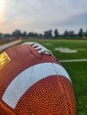 Vertical closeup of a football ball with a blur football field background Royalty Free Stock Photo