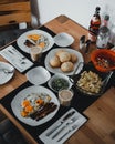 Vertical closeup of a freshly cooked breakfast table with bread and egg dishes, wooden background