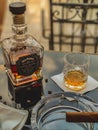 Vertical closeup of a glass and bottle of whiskey on a black glass table
