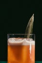 Vertical closeup of glass of pineapple trainwreck cocktail on black background