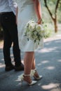 Vertical closeup of groom and bride holding hands, white bride holding a bouquet of white roses Royalty Free Stock Photo