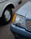 Vertical closeup of a headlight of a blue Mercedes-Benz SL 500 blurred asphalt background