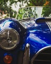 Vertical closeup of a headlight of a blue retro car