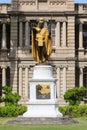 Vertical closeup of King Kamehameha statue in downtown Honolulu, with Iolani palace background