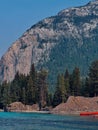 Vertical closeup of a lake, tree, rocky, forested mountain clear sky background