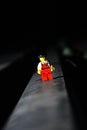 Vertical closeup Lego movie hero standing on a black surface with dark, blurred background