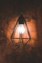 Vertical closeup of a lit lamp in a stylish black frame against a brown wall Royalty Free Stock Photo