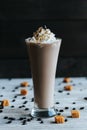 Vertical closeup of a milkshake on the white towel covered with sweets, dark blurred background