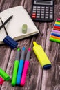 Vertical closeup of an open notebook with a black pencil, eraser, colored markers, and a calculator Royalty Free Stock Photo