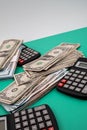 Vertical closeup of a pack of dollars black calculators around on the green background