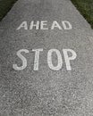 Vertical closeup of paint on a concrete path writing "stop ahead"