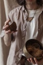 Vertical closeup of a person in a beige linen clothing holding an exocarp of a coconut Royalty Free Stock Photo