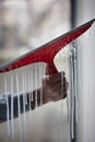 Vertical closeup of a person cleaning the window with a red squeegee Royalty Free Stock Photo