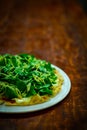 Vertical closeup of a plate of spinach with cheese on a wooden table