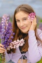 vertical closeup portrait little girl smiling and holding bouquet of purple lupins Royalty Free Stock Photo