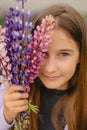 vertical closeup portrait little girl smiling and holding bouquet of purple lupins Royalty Free Stock Photo