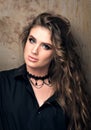 Vertical closeup portrait of young beautiful woman in black shirt posing in front of a metal wall Royalty Free Stock Photo