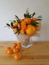 Vertical closeup shot of a beautiful bouquet with roses, oranges, and tangerines on the table