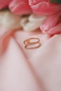 Vertical closeup shot of a beautiful gold ring on a pink fabric with pink roses in the background Royalty Free Stock Photo