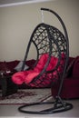 Vertical closeup shot of a black hanging chair swing with red cushions