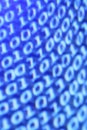 Vertical closeup shot of a blue blurred screen displaying binary codes - a digital concept