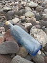 Vertical closeup shot of a blue water bottle with a note inside on the rocks by the beach Royalty Free Stock Photo