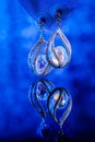 Vertical closeup shot of classy earrings with diamonds reflected in the blue background Royalty Free Stock Photo