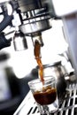 Vertical closeup shot of coffee machine brewing fresh espresso in glass cup