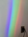 Vertical closeup shot of a colorful rainbow reflected on a white wall