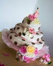 Vertical closeup shot of a cute dotted cake with flowers and a doll figure for girl birthdays