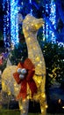 Vertical closeup shot of a cute glowing yellow reindeer with a red ribbon in a park during Christmas