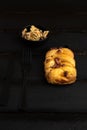 Vertical closeup shot of delicious small puff pastry cake with nuts on black wooden background