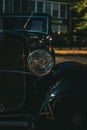 Vertical closeup shot of details on a shiny antique automobile in the dark