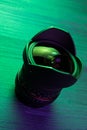Vertical closeup shot of a digital camera lens under a green neon light on a table Royalty Free Stock Photo