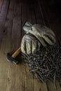 Vertical closeup shot of dirty white gloves on a hammer and a stack of nails on the wooden ground Royalty Free Stock Photo