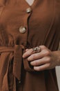 Vertical closeup shot of a female wearing a brown dress and a metallic leaf-shaped ring